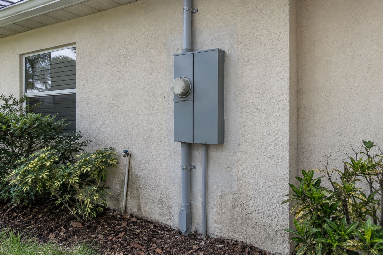 A home's electric meter and meter can on an exterior wall